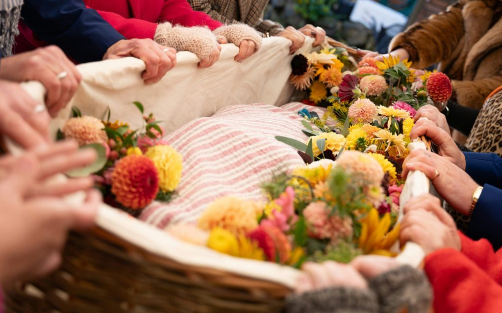 People carry a flower-covered wicker casket.